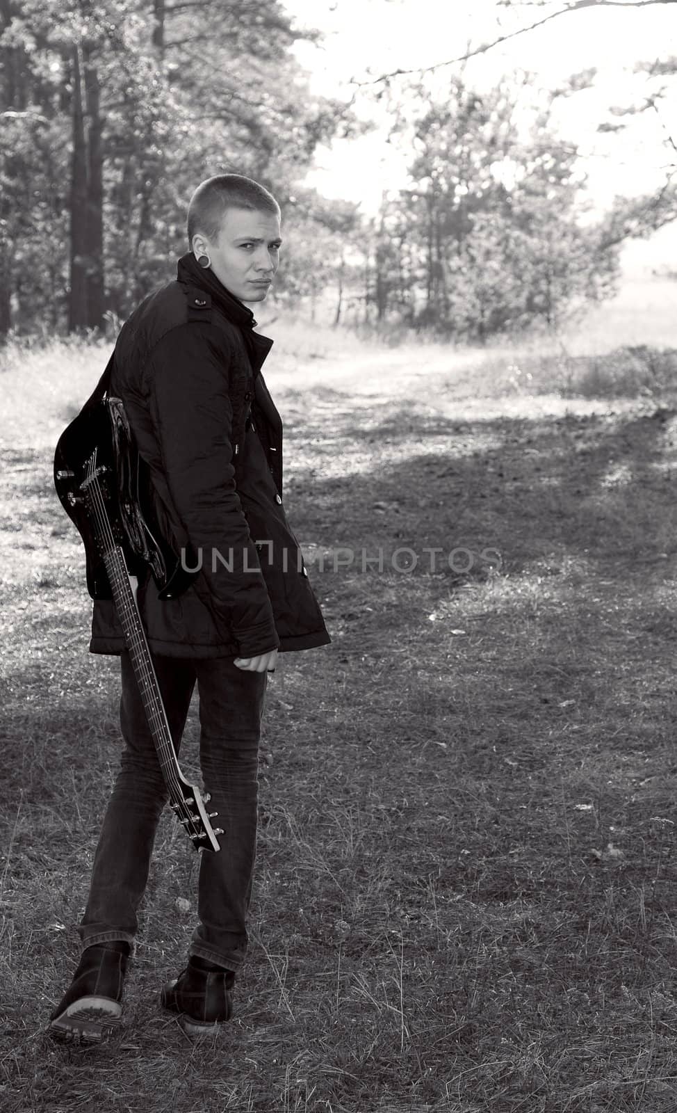 teen musician with a guitar in the autumn forest