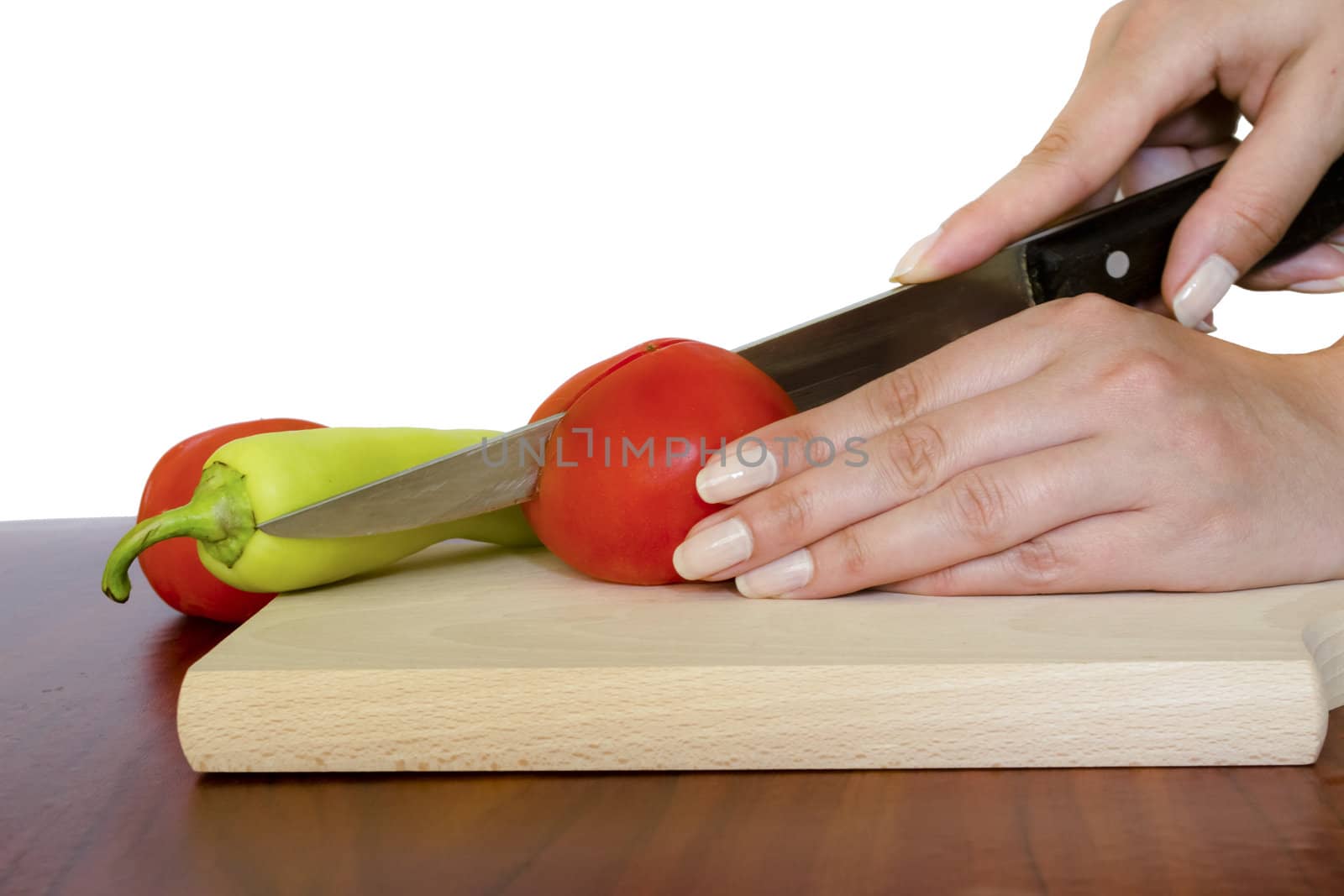 Cutting tomato on wooden board by vician