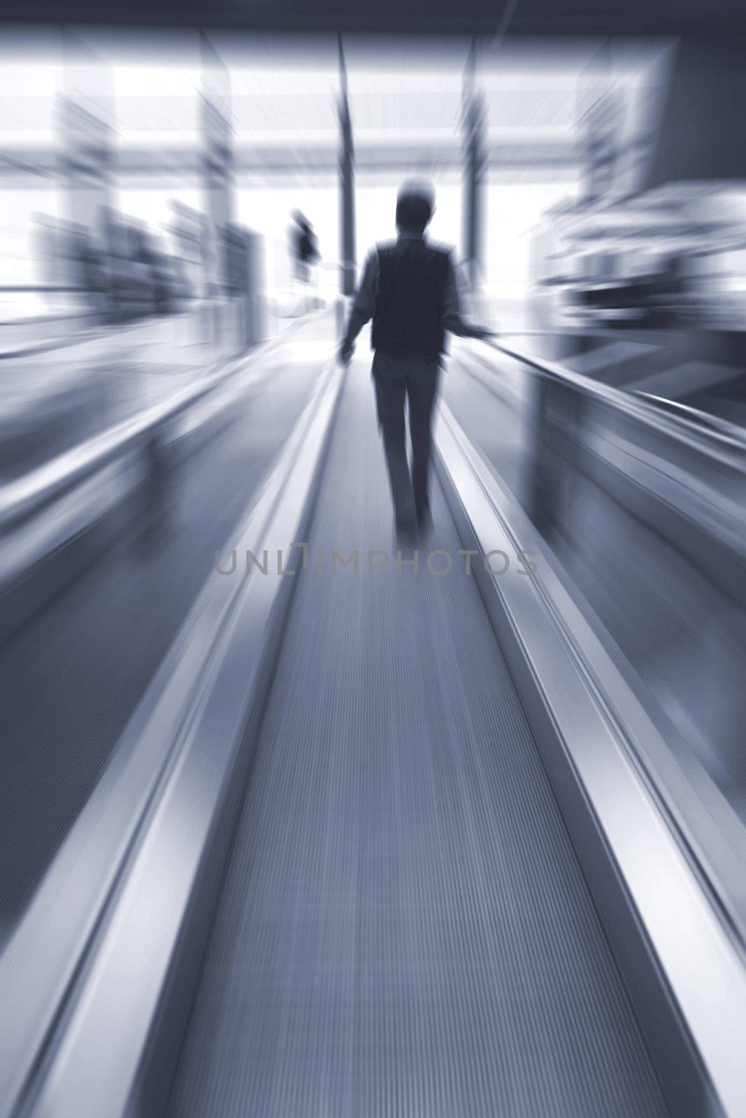 Young male hurrying down an escalator in a business building.