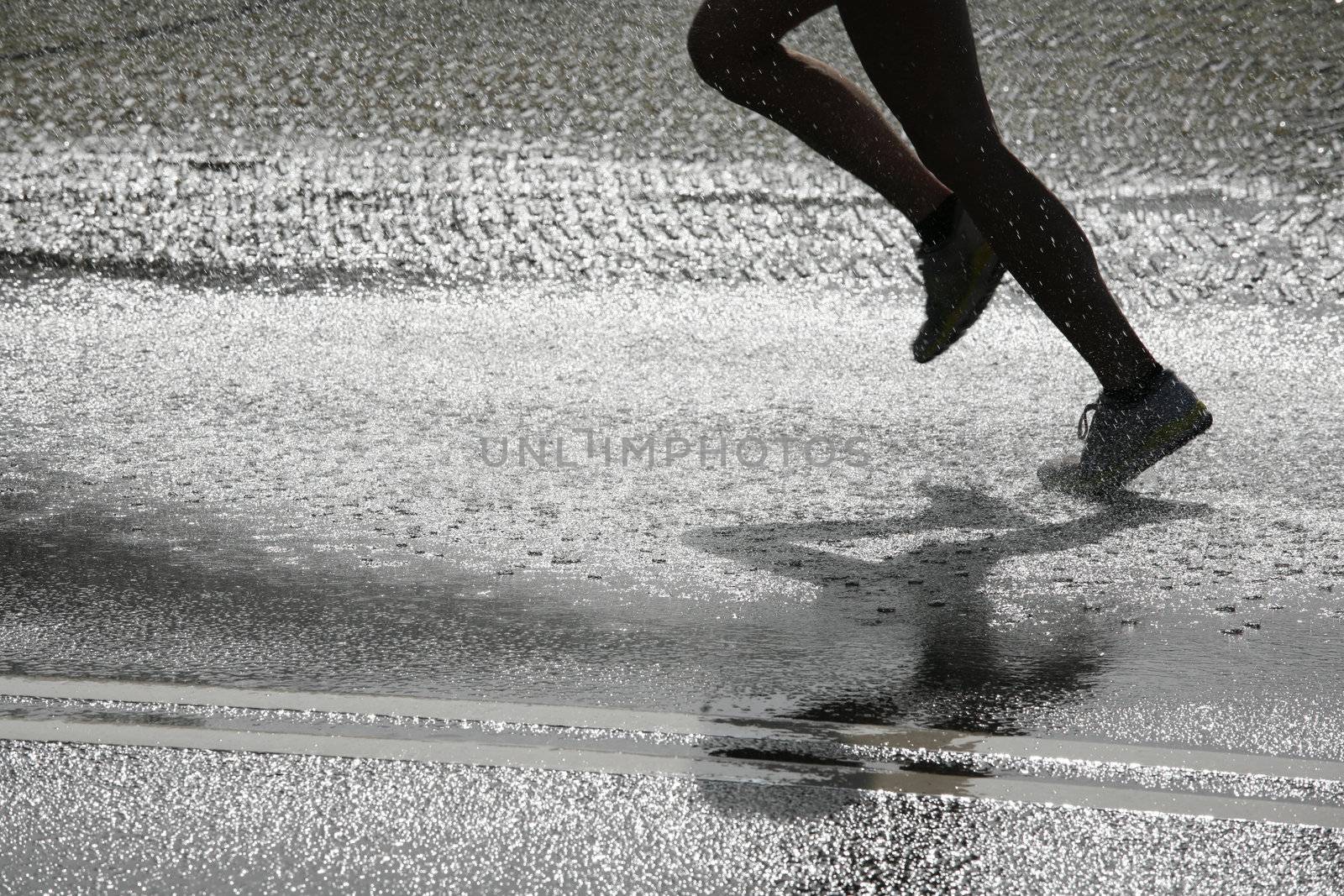 The last sprint in the marathon. The runner passing a jet of water for cooling down the runners in the heat.