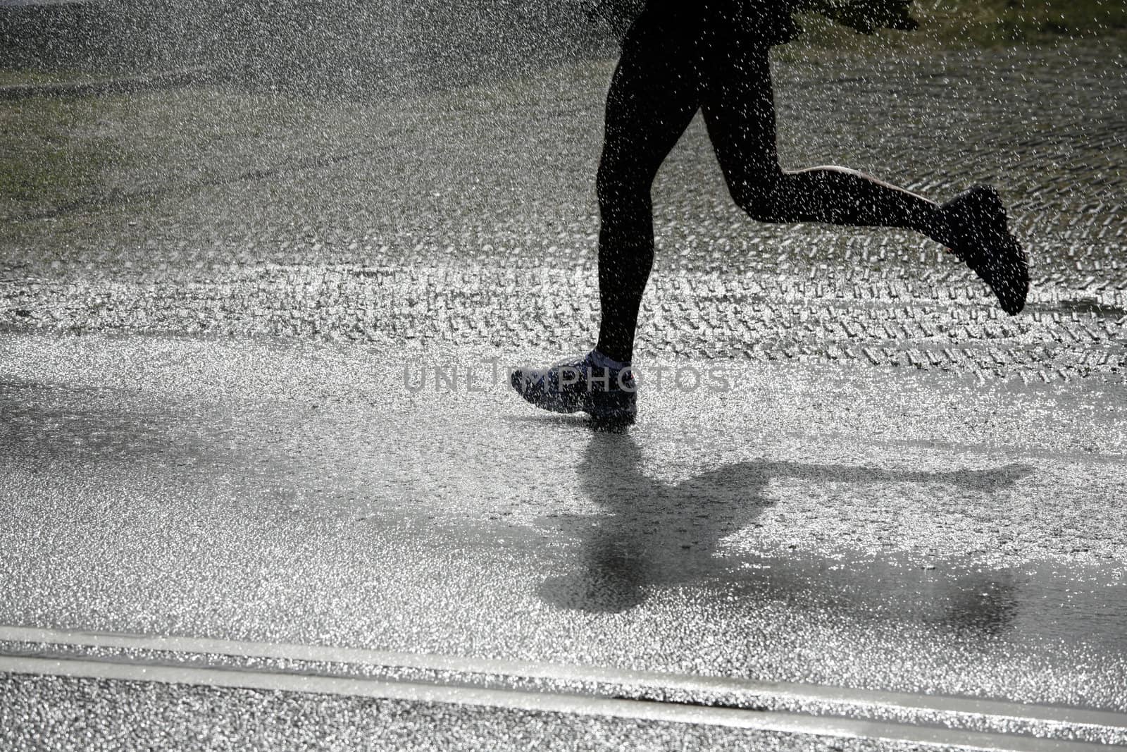 Marathon runner passing a jet of water for cooling down the runners in the heat.