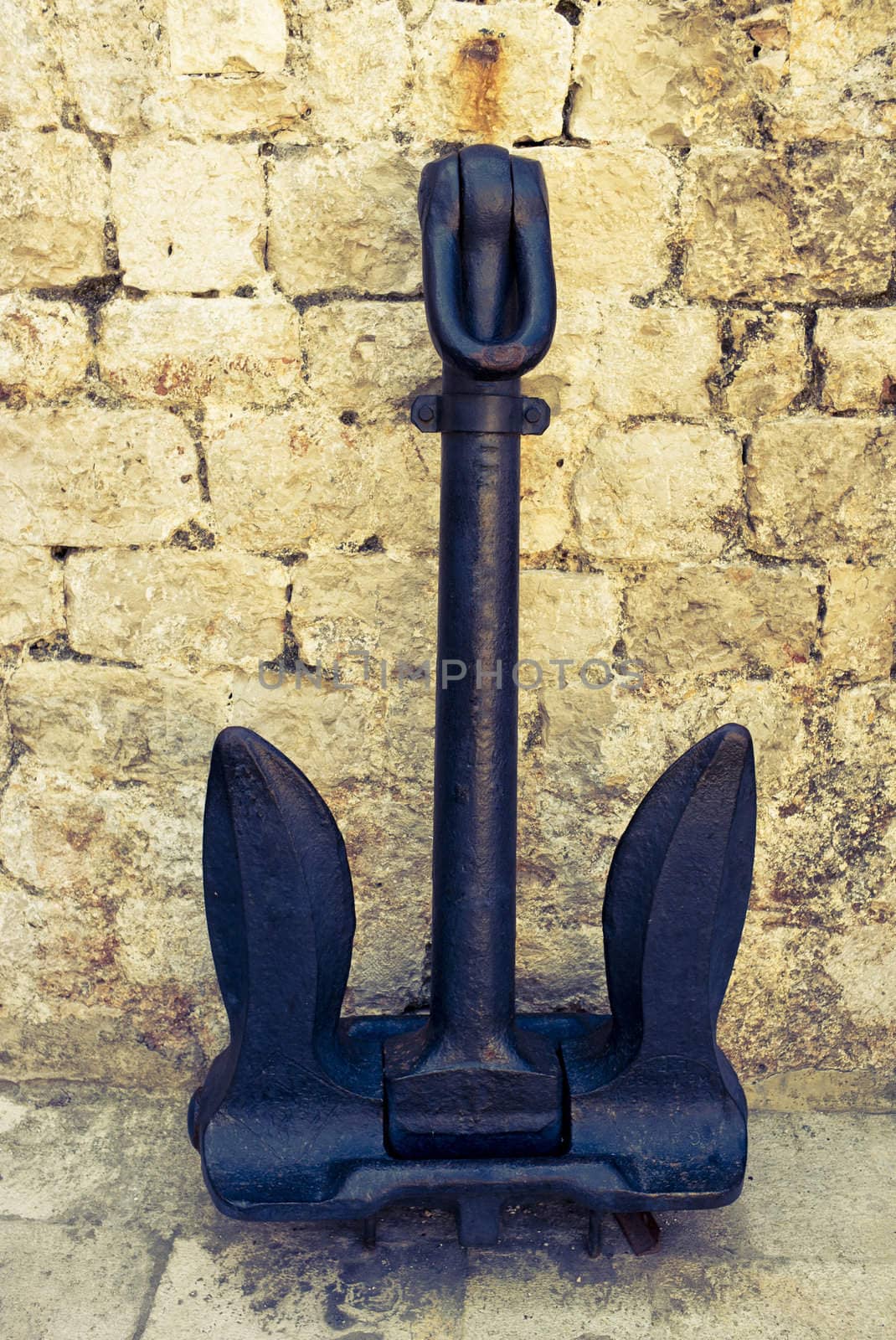 Old Croatian anchor in front of stone wall. Image is cross processed to reflect time and age.