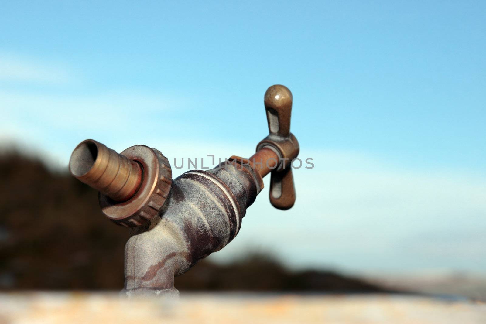 concept for clean mountain spring water with an outdoor water tap against a blue cloudy sky
