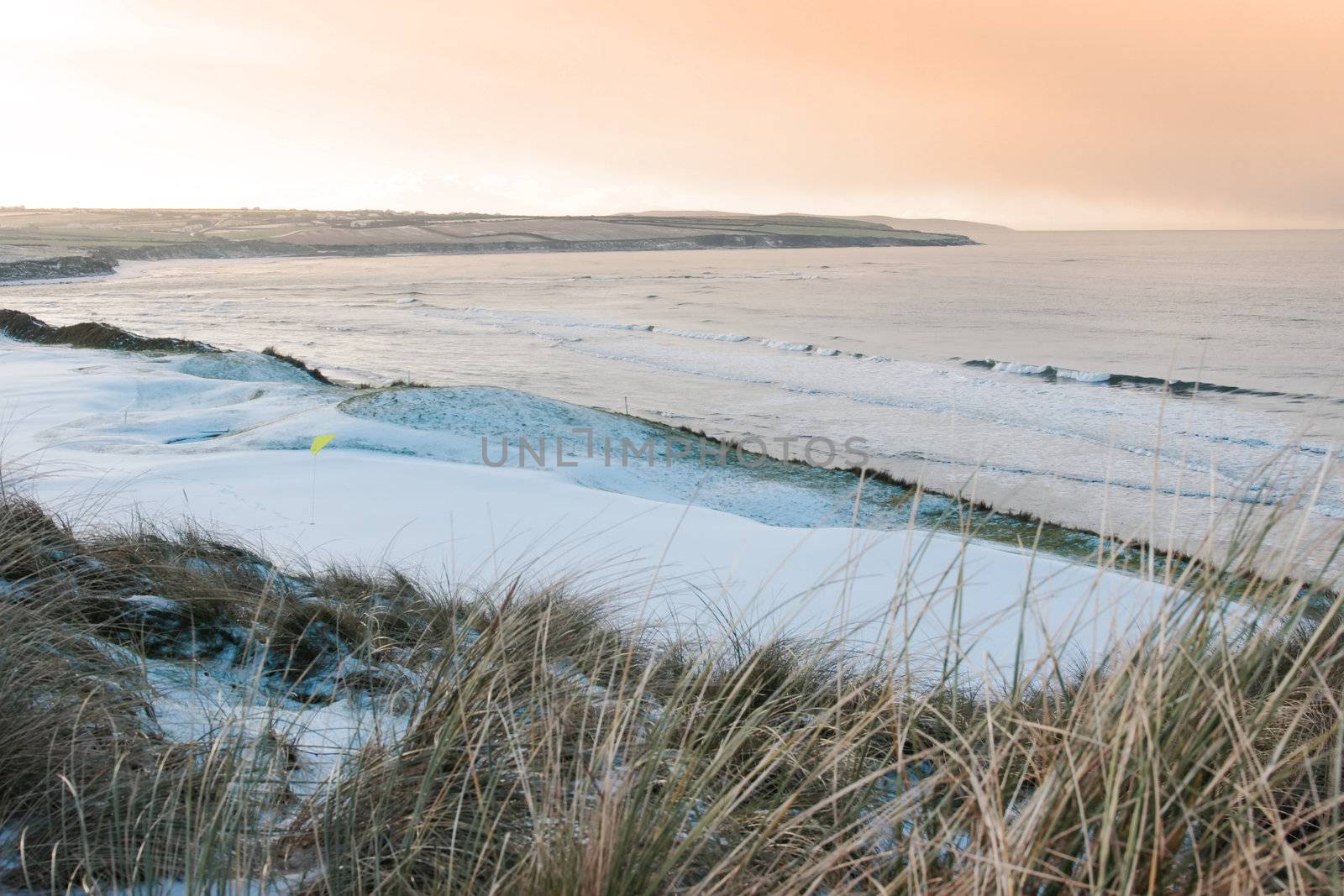 a snow covered links golf course in ireland in winter weather at sunset