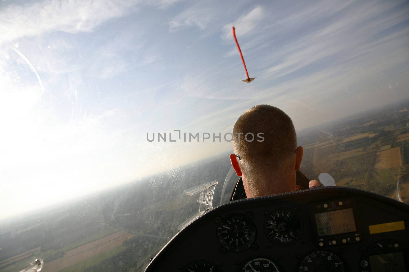 Glider pilot in the air with his plane gliding away in the low evening sun.