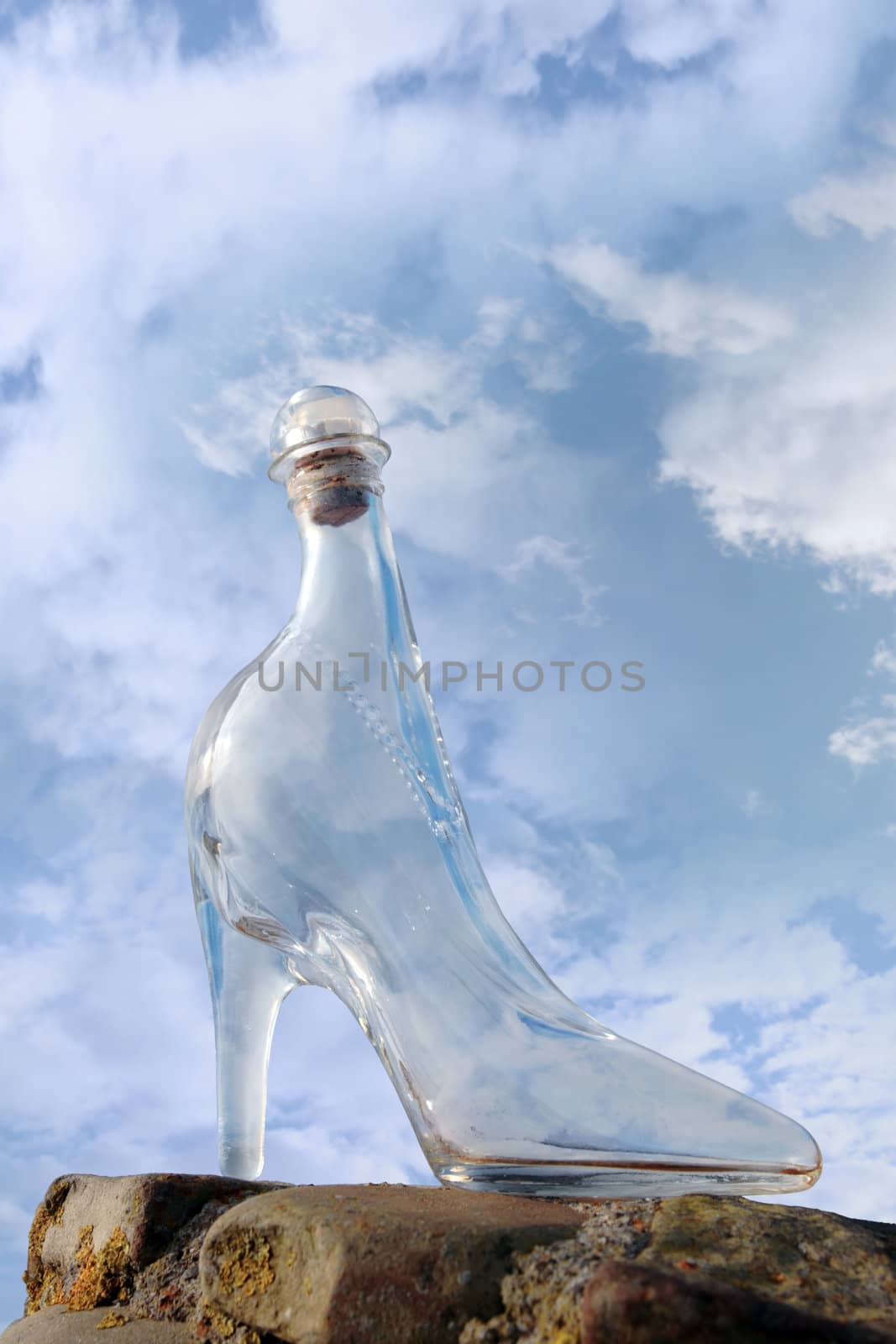 a glass slipper on a stone surface with a cloudy blue sky background