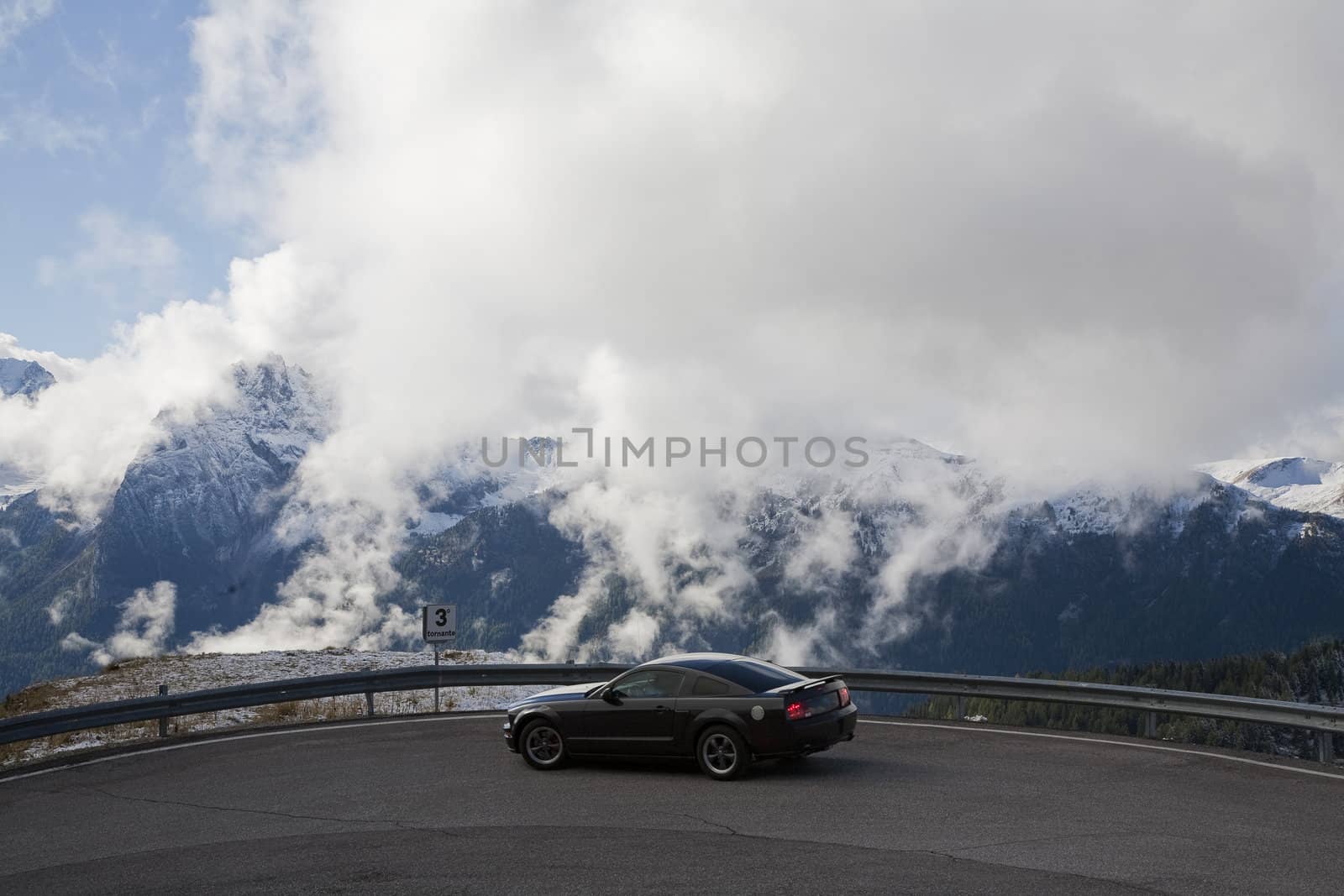 Low hanging clouds behind automobile in a hairpin bend in the Dolomites - Italy.