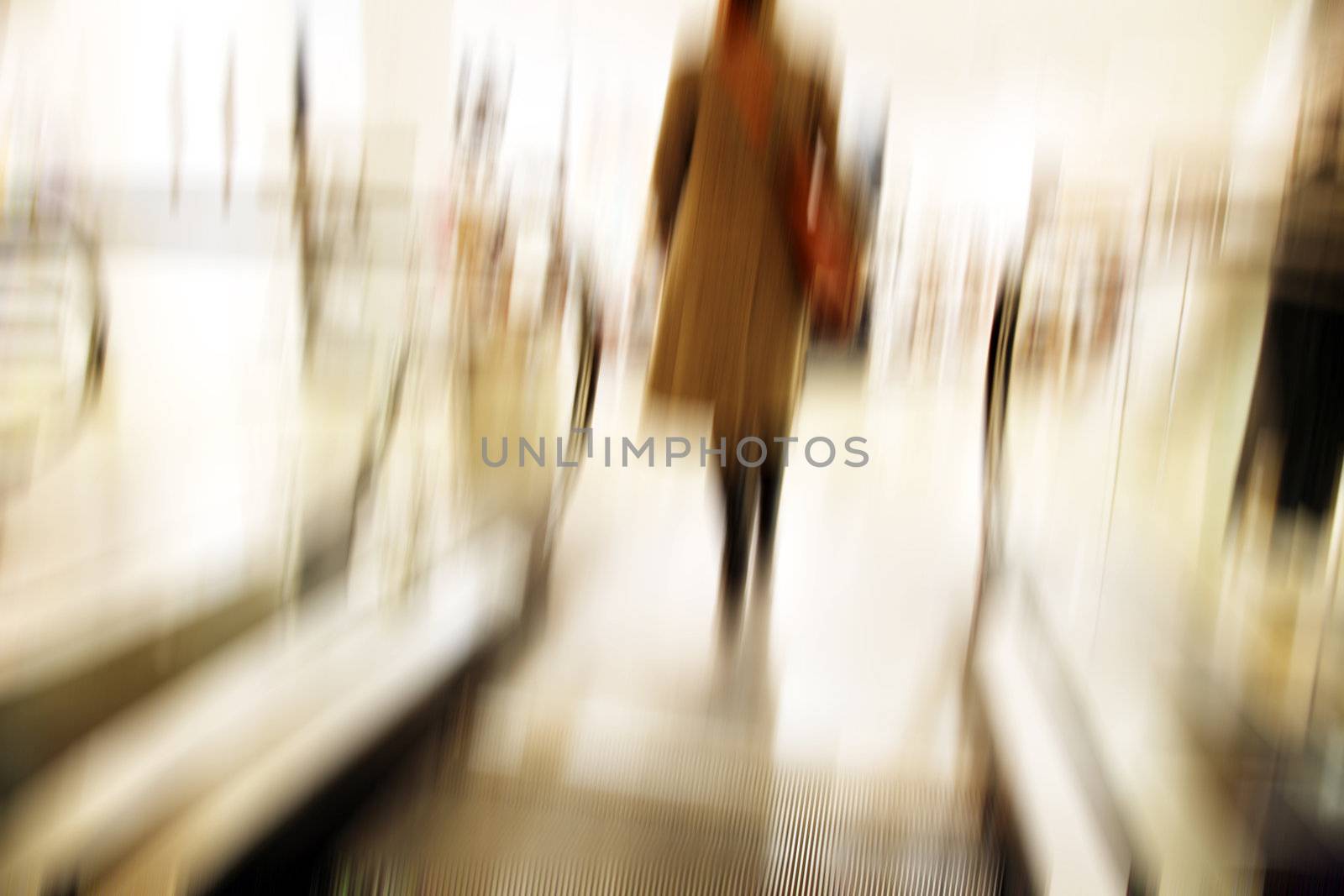 Female going up with the escalator in a department store - motion blur.