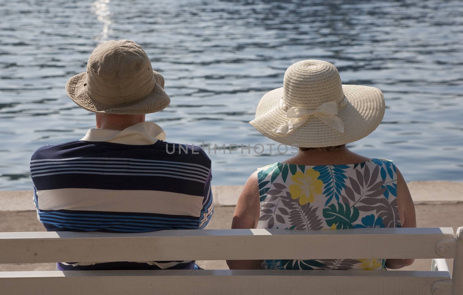 Mature couple on bench enjoying the sun and their vacation in Croatia.