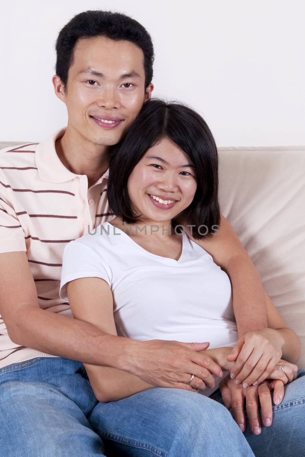 Young Asian couple sitting on sofa with smiling face. 