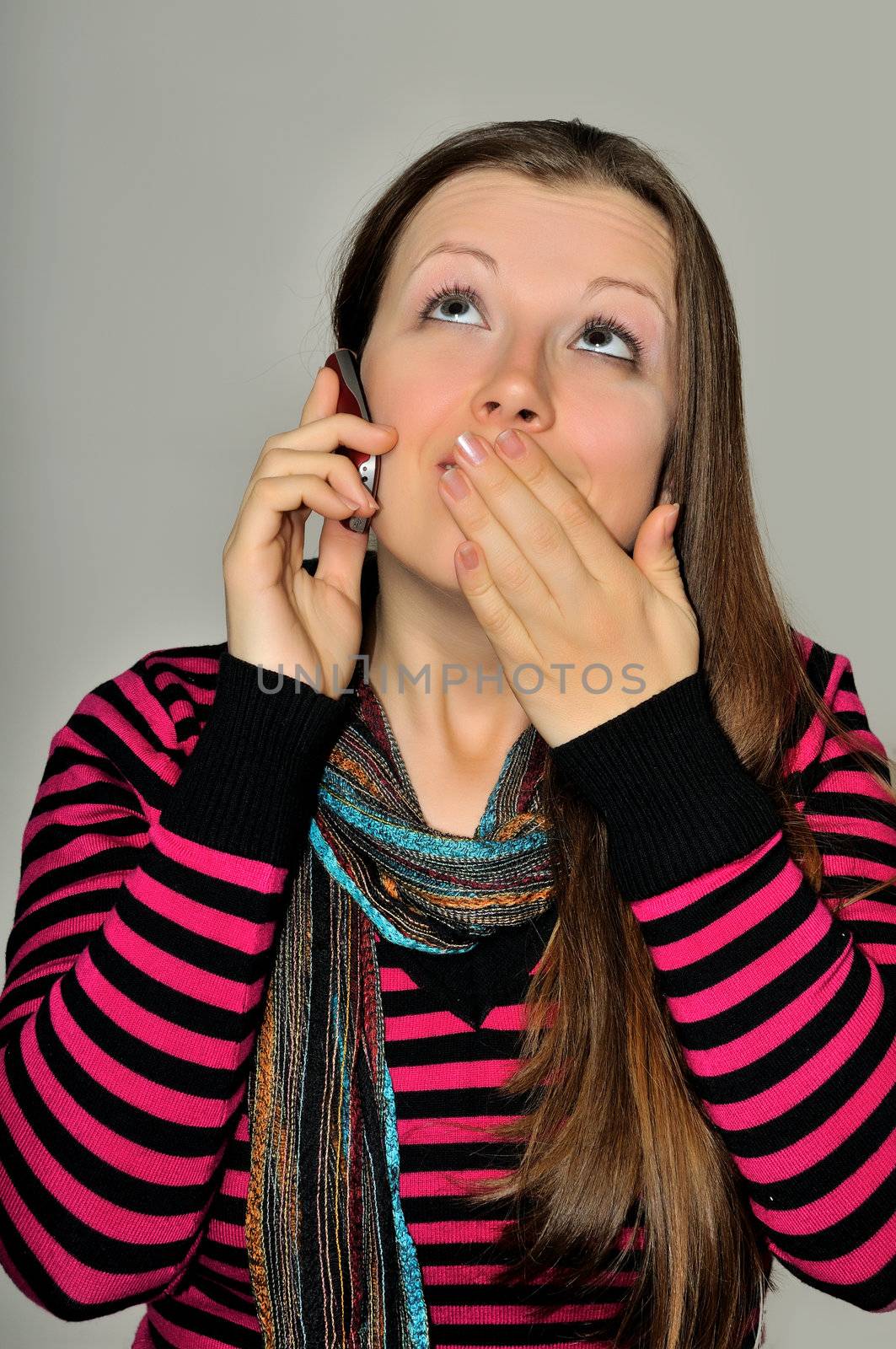 A young girl emotionally expressive talking on a mobile phone