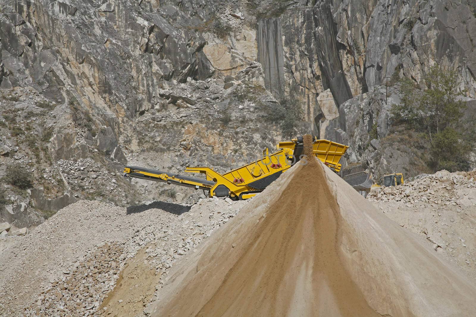 Machine crushing small pieces of marble to road materials in the mountains near the Italian city Carrara
