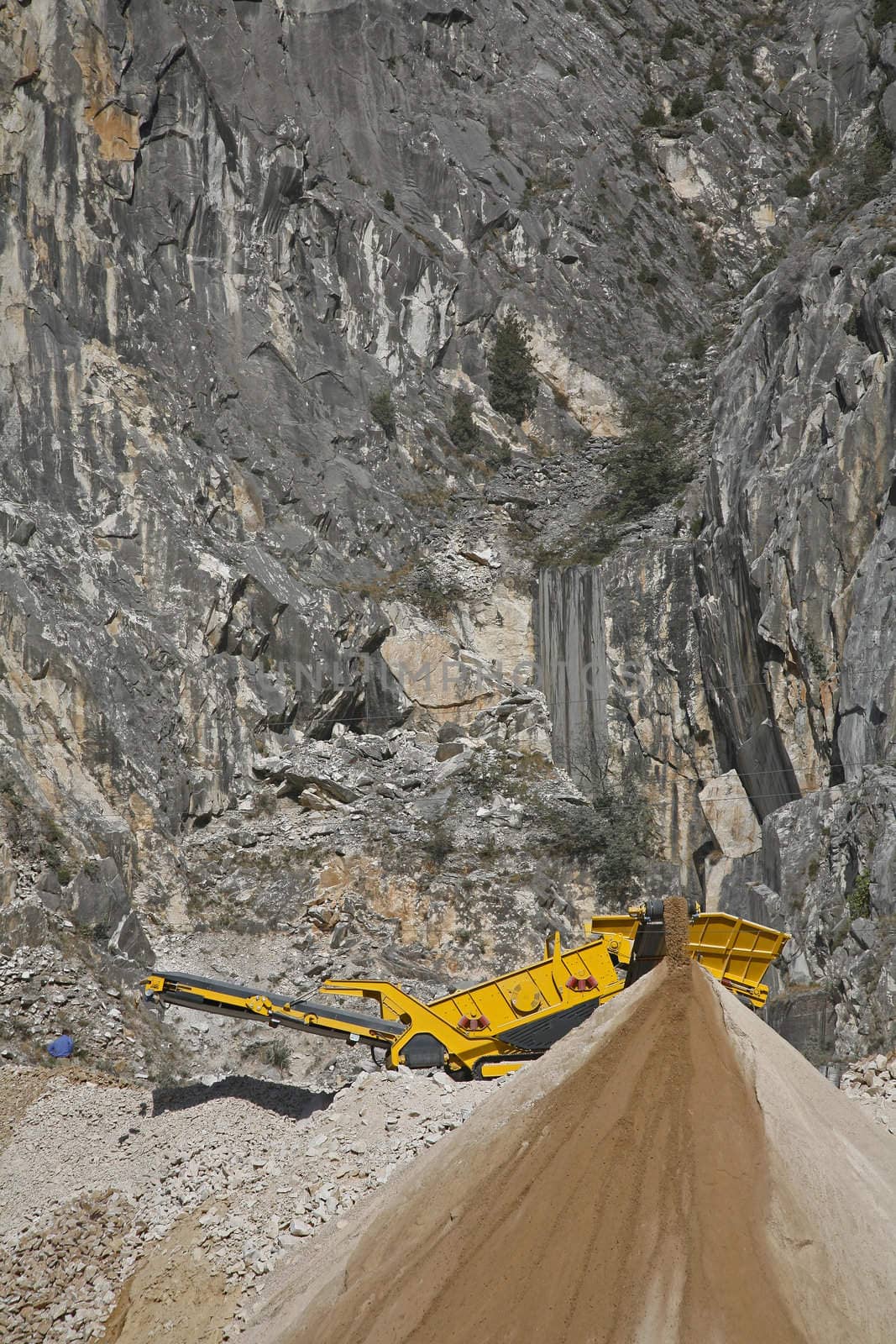 Machine crushing small pieces of marble to road materials in the mountains near the Italian city Carrara.