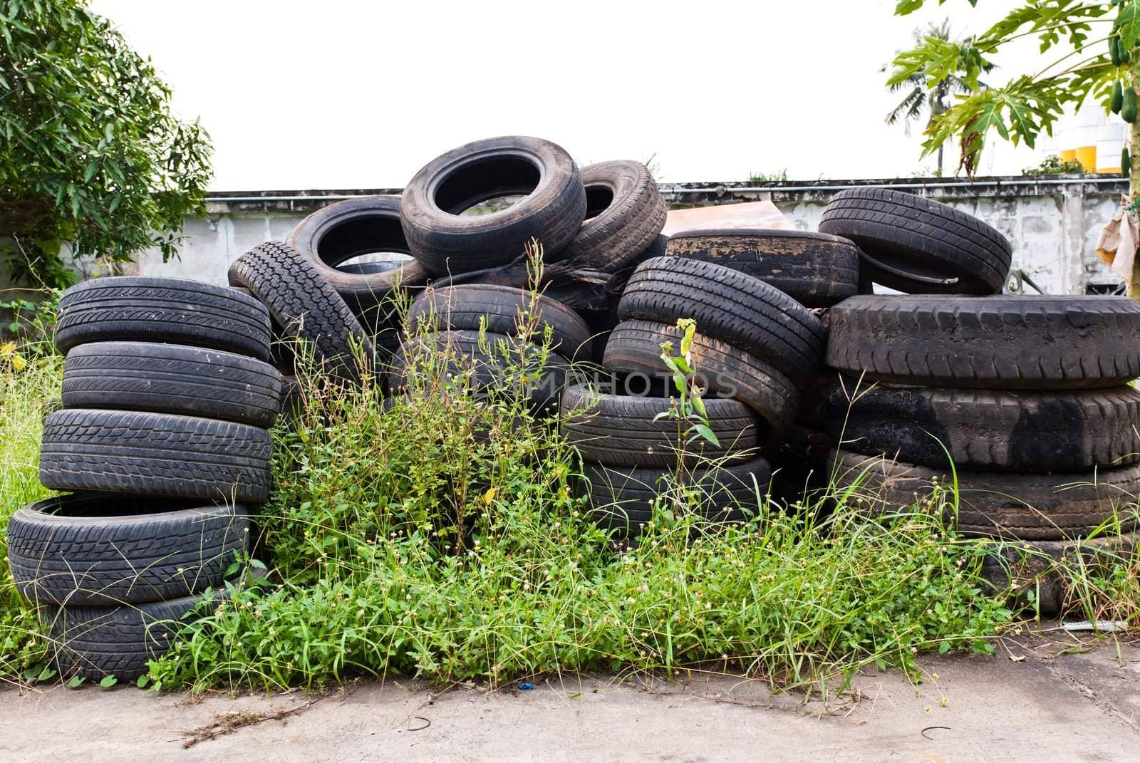 Old road tires stacked on grass land as background
