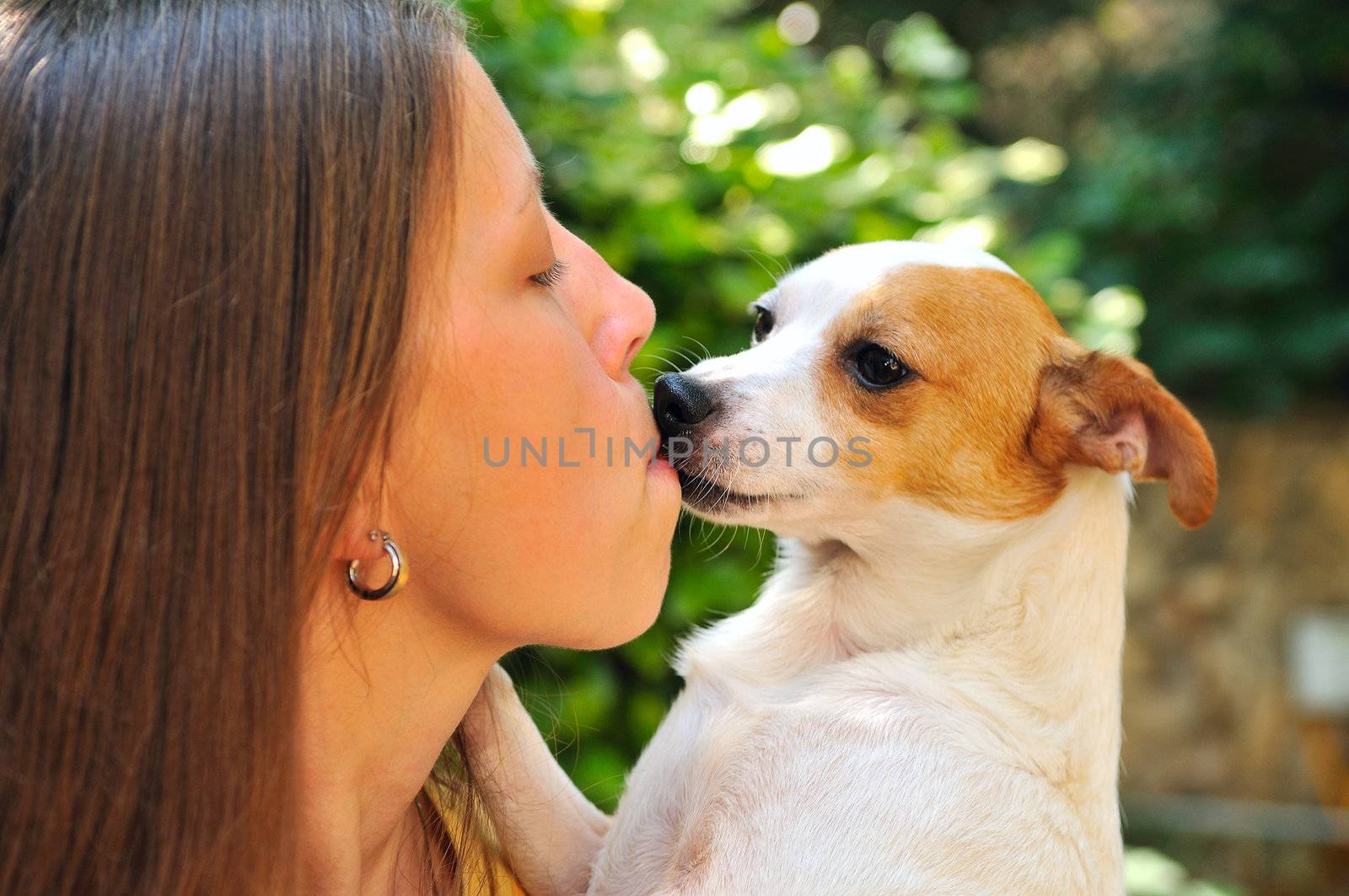 A girl holding a small dog who loved her kisses