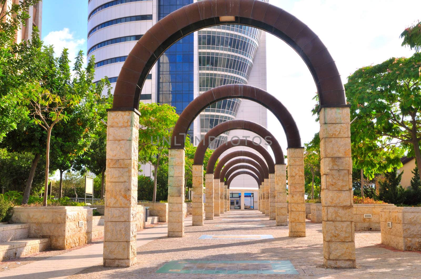 Alley of metal arches on stone pillars leading to an office building