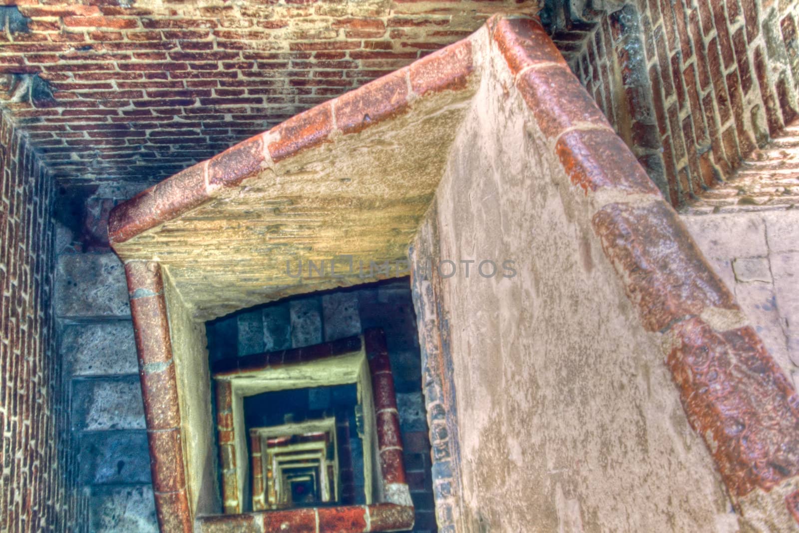 Winding square staircase inside old brick-walled tower.