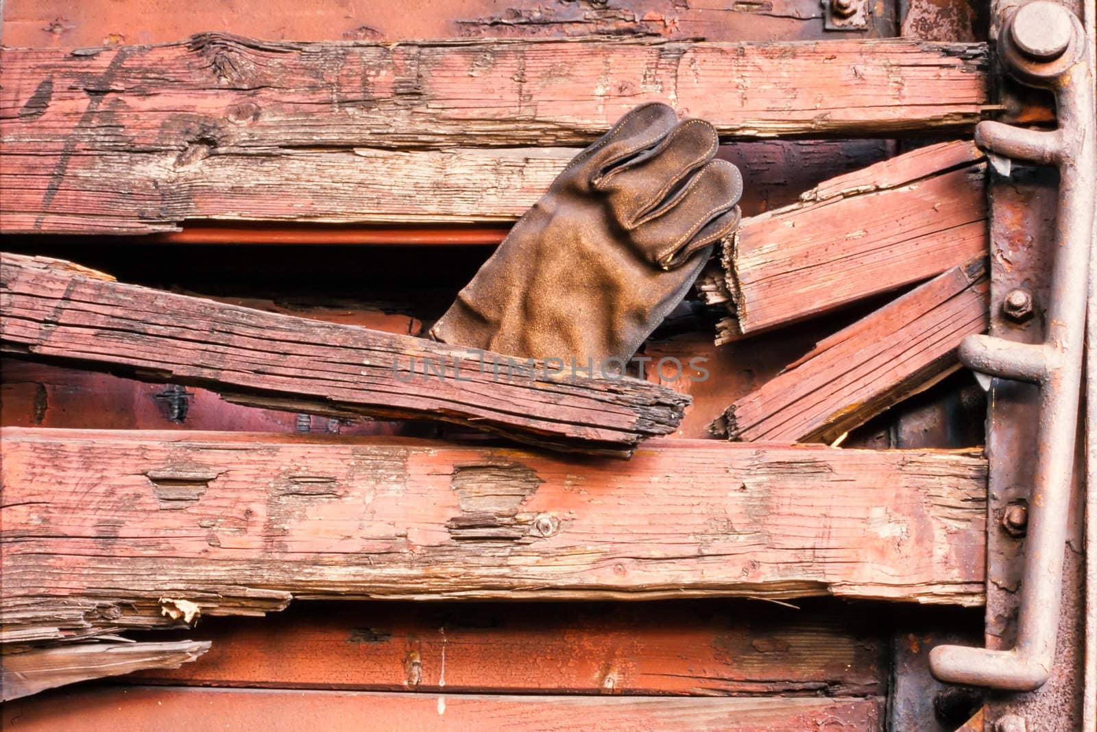 Abandoned old leather glove sticking in wooden wall of broken boards.