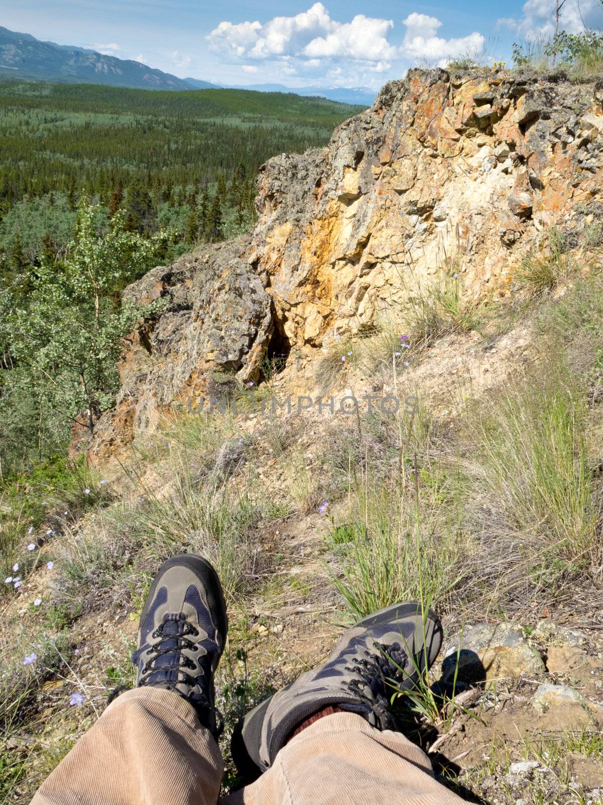 Tired hiker taking a rest overlooking rocky terrain and beautiful scenery in boreal forest of Yukon Territory, Canada.