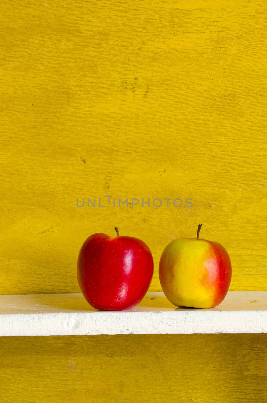 Apples on white shelve yellow wall background. by sauletas