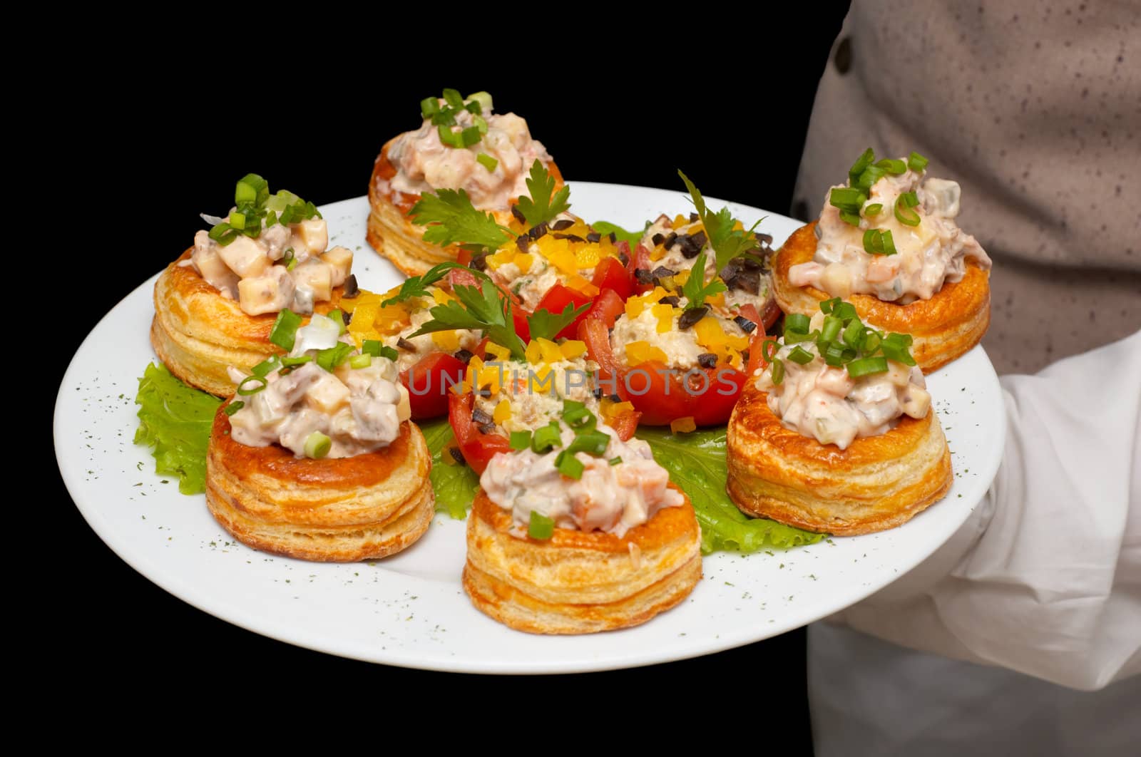 tartlets with salad on dish, held by waiter