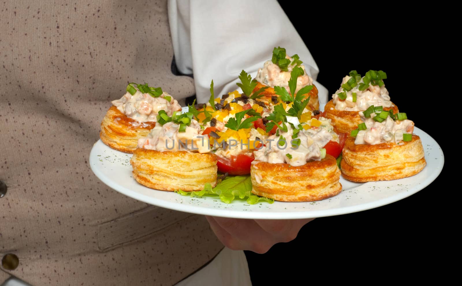 tartlets with salad on dish, held by waiter