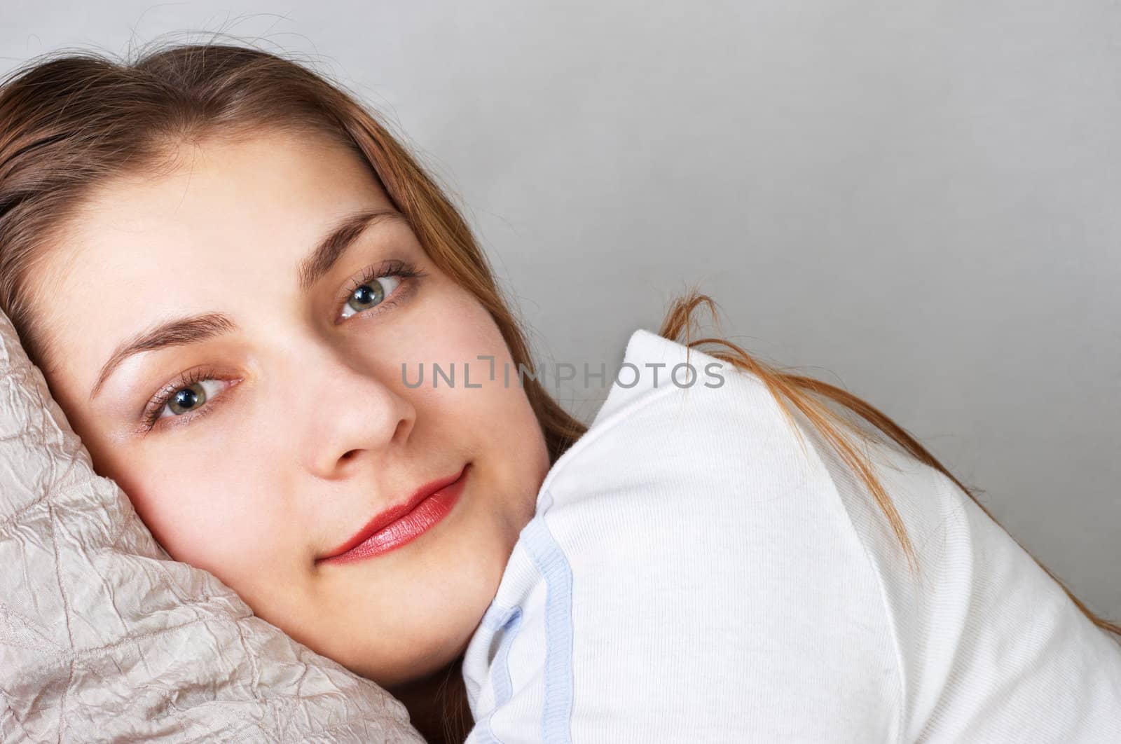daydreaming beautiful young woman lying on pillow