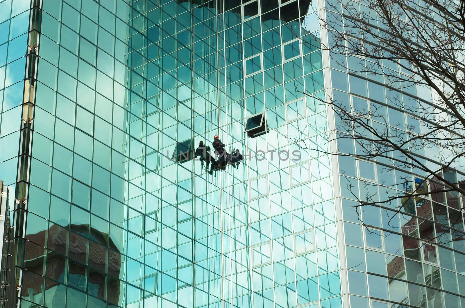 worker climbing at mirror wall of office building