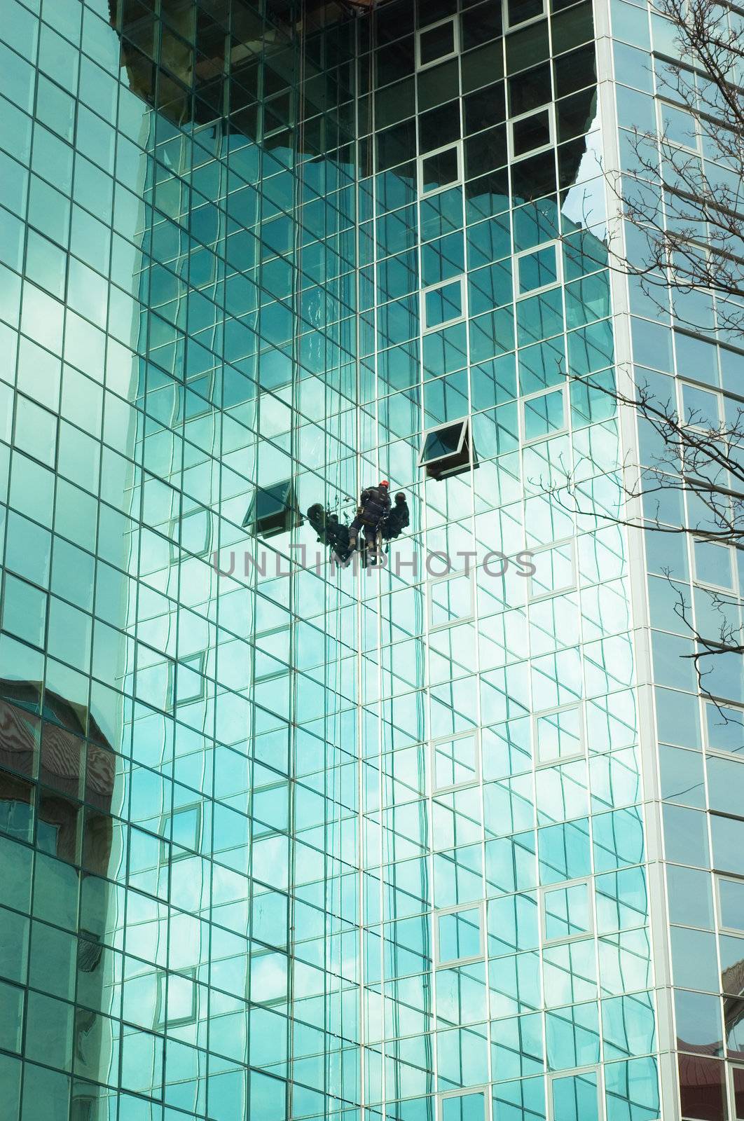 worker climbing at mirror wall of office building