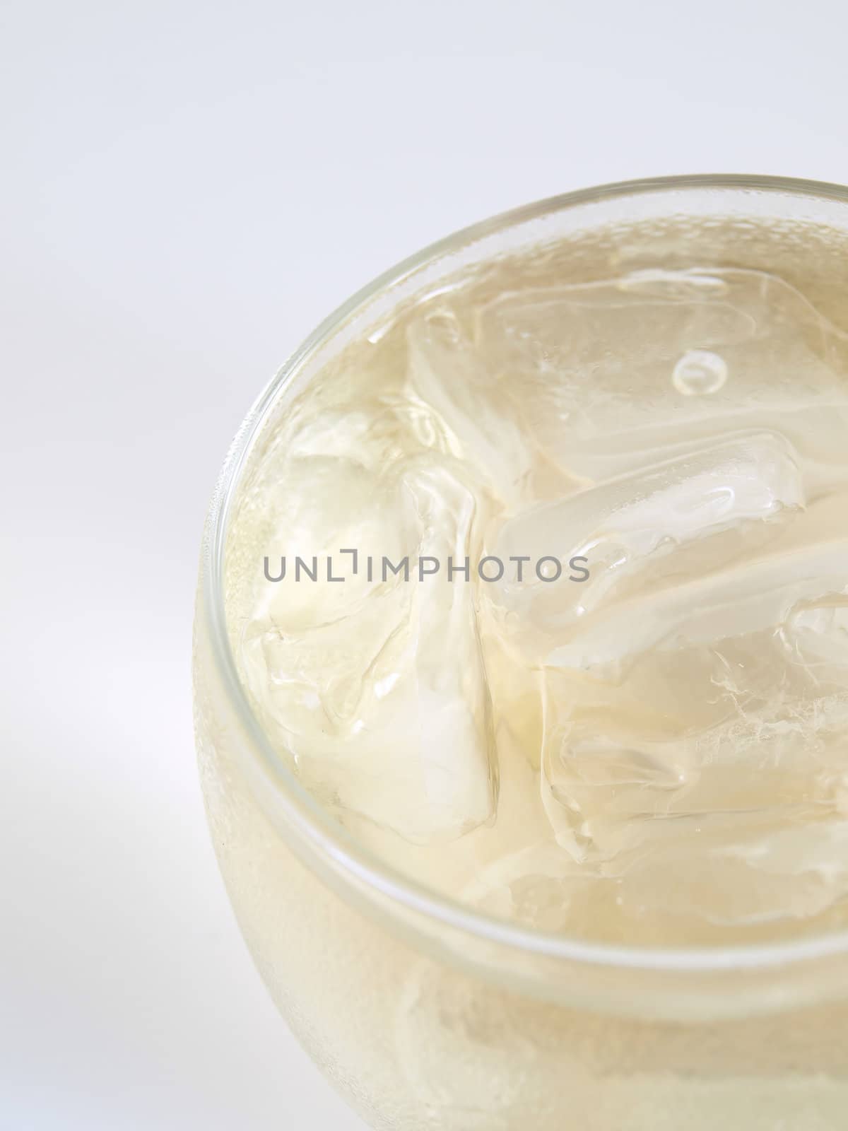 Close side framed view of an alcoholic beverage over ice in a small clear glass, studio isolated on a white background.