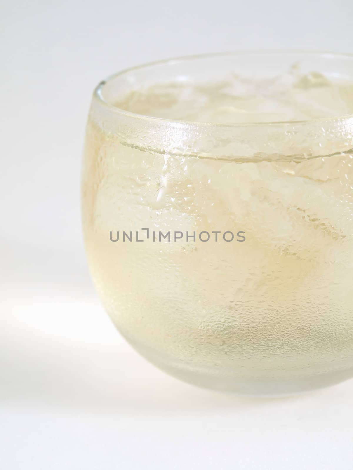 Close side view of an alcoholic beverage over ice in a small clear glass, studio isolated on a white background.