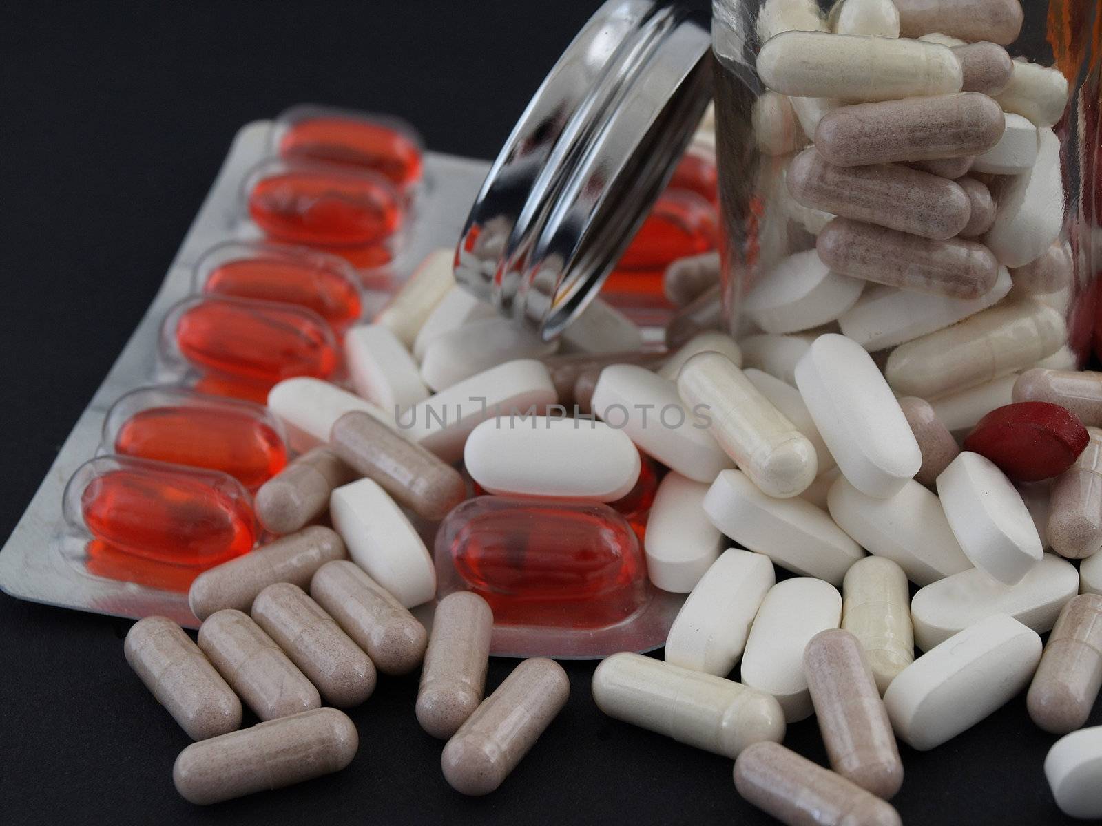 Various pills and pill bottles, studio isolated over a black background.