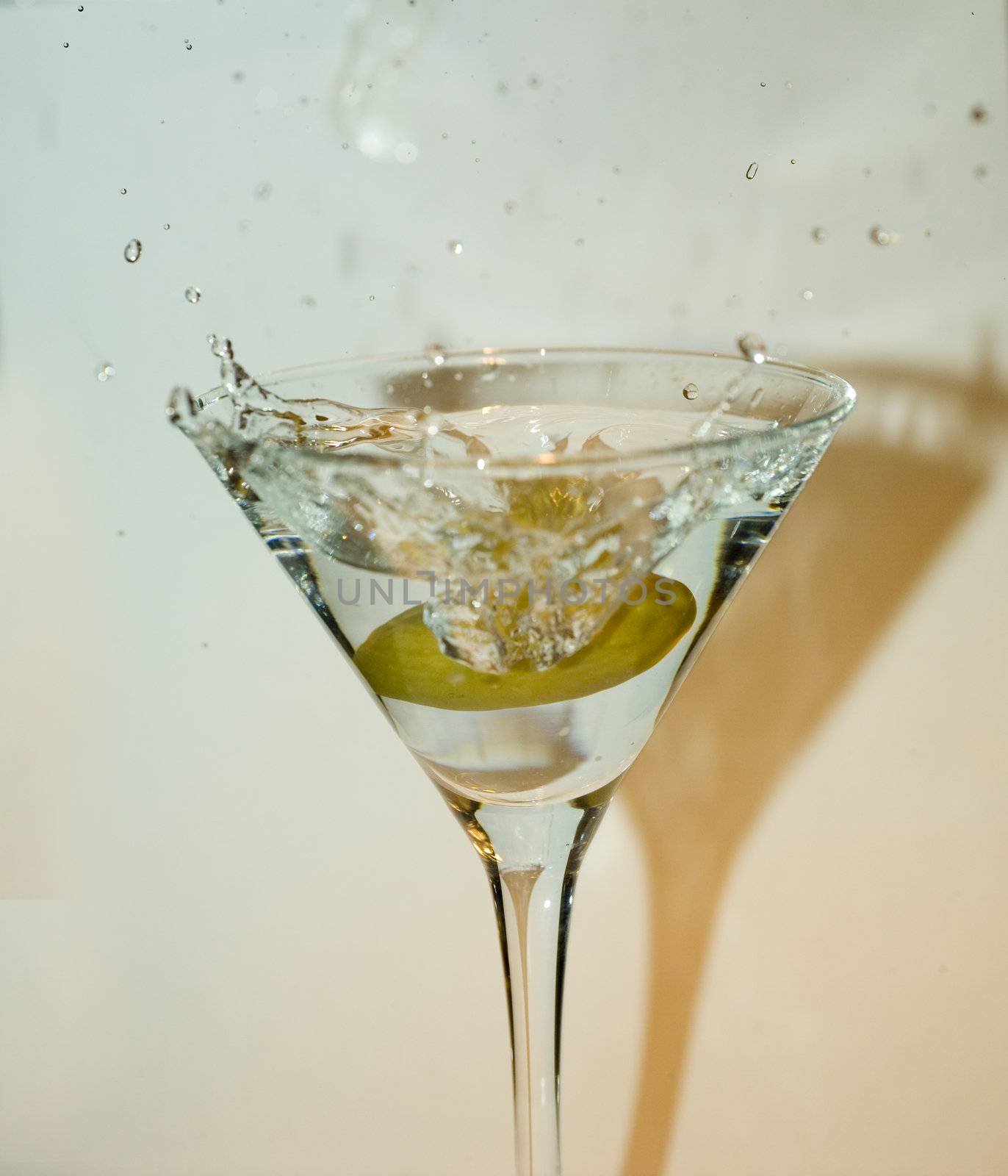 big green olive splashing into martini drink