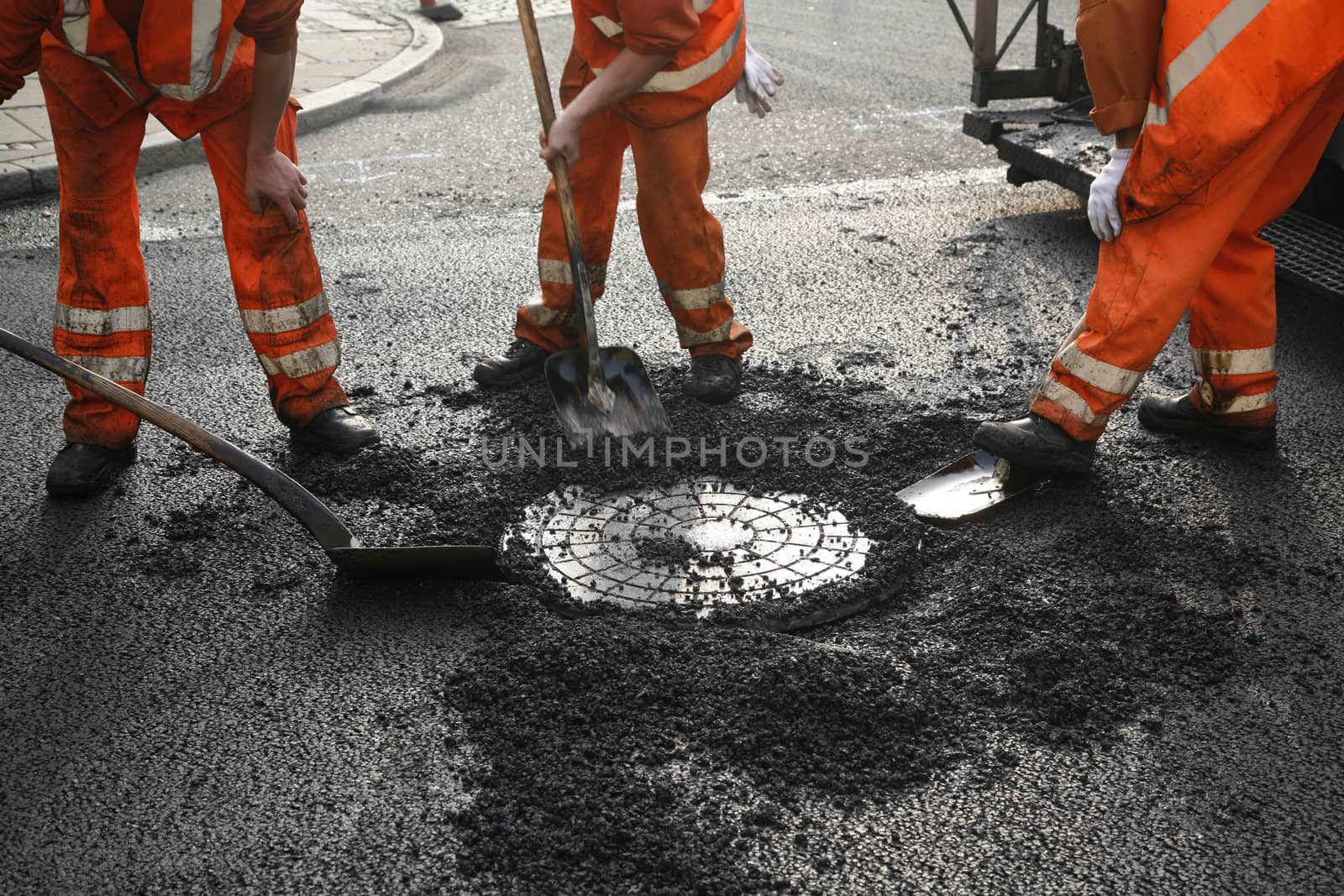 Team of Danish asphalt workers lifting a manhole.