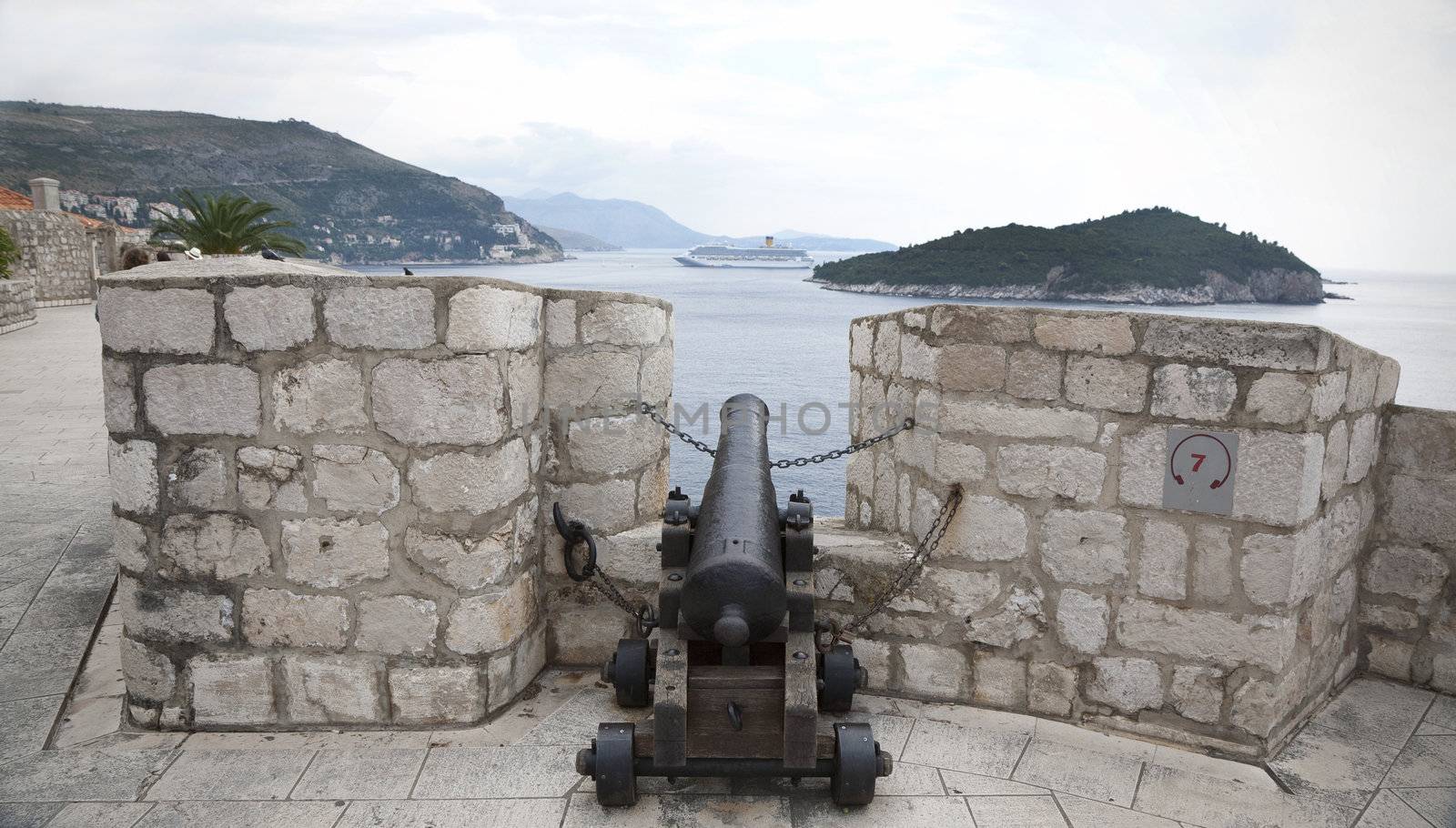 Ancient cannon at the town wall of Dubrovnik, Croatia pointing directly againt a cruiser in the Adriatic Sea outside.