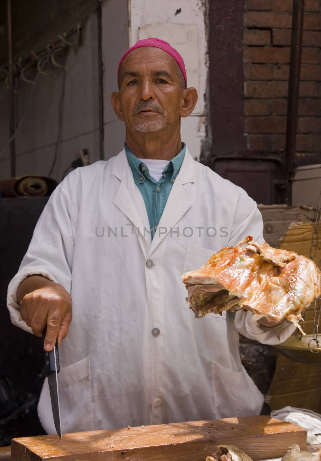 Man holding a joint of mutton at a butchers stall in the main souk of Marrakesh, Morocco.