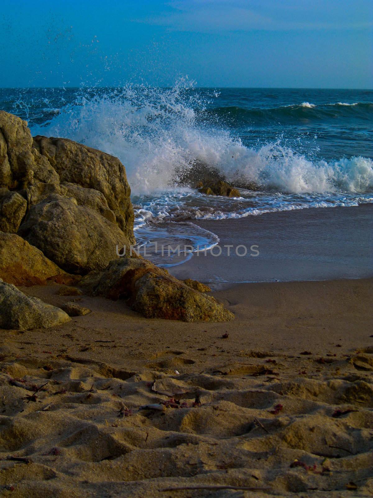 Waves crash on rocky beach by pennypix