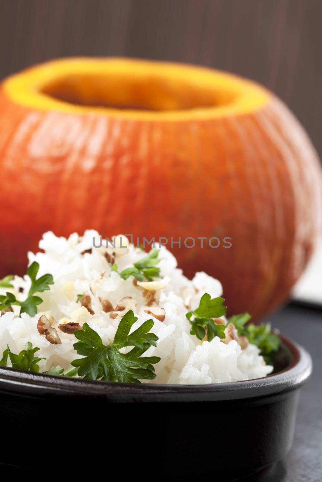 Rice with fresh chopped nuts and parsley and a pumpkin in the background