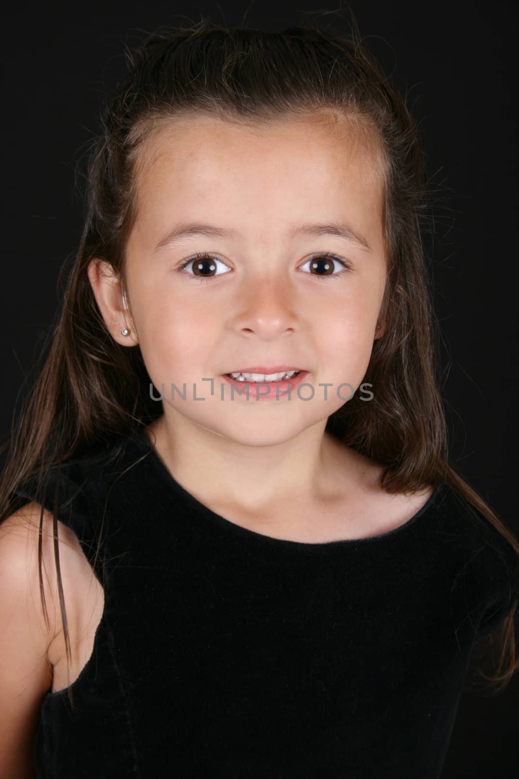 Cute little brunette girl against a black background