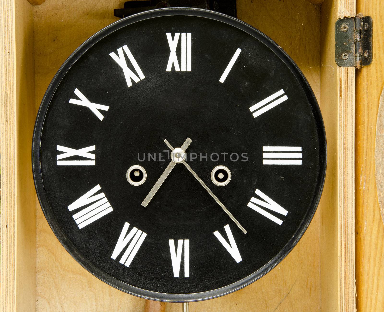 Ancient black clock with roman numbers and arrows. Antique clock in wooden box.