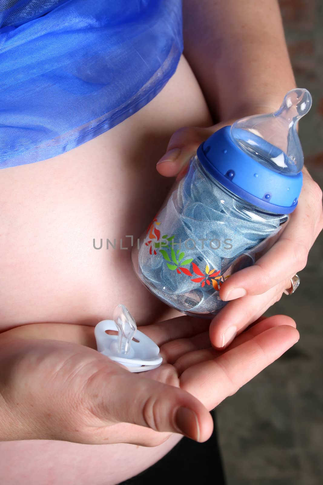 Heavily pregnant lady holding a bottle and dummy