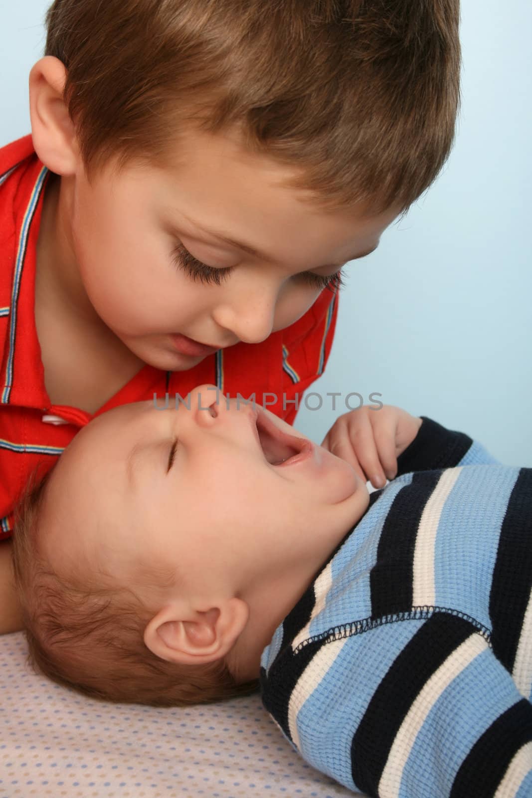 Big brother looking at his baby brother yawning