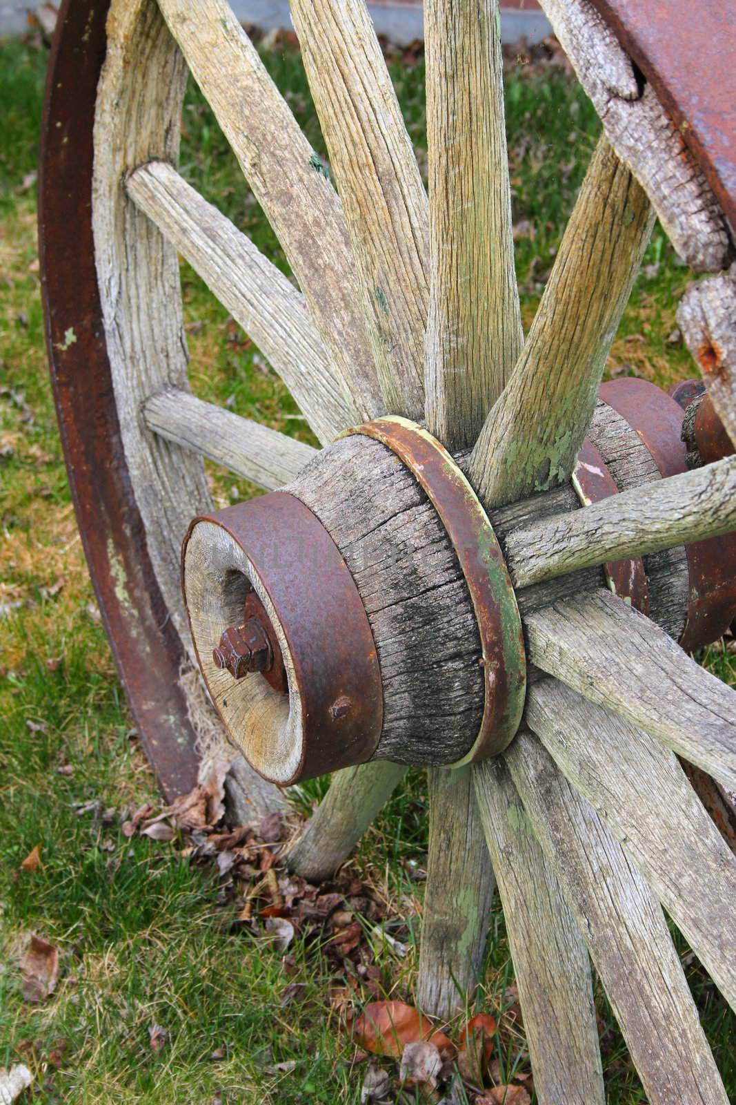 Rustic worn wooden wagon wheel on grass