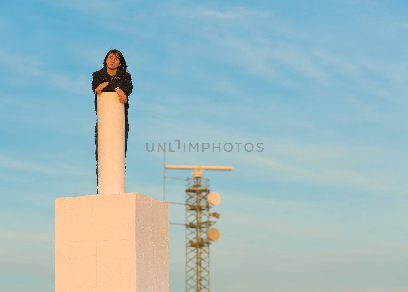 Teenager on top of a structure with surveillance equipment in the background, a concept