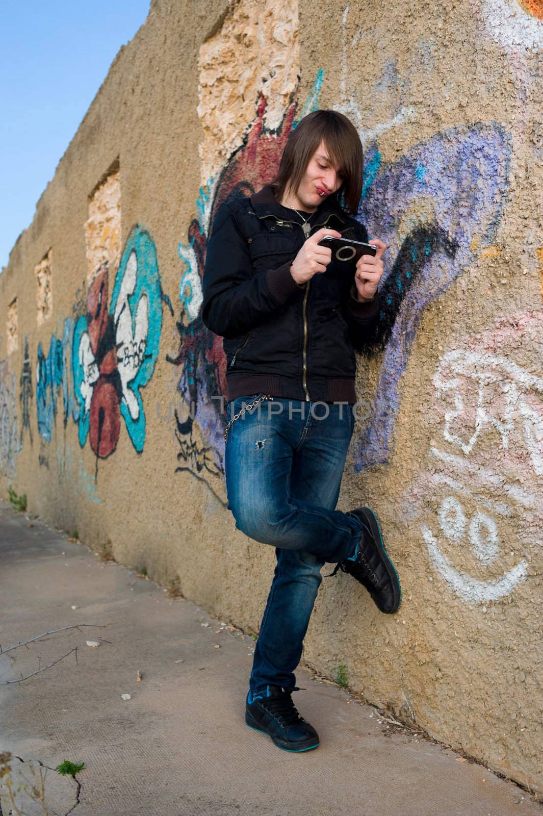 Teen playing with a console in a grunge urban setting