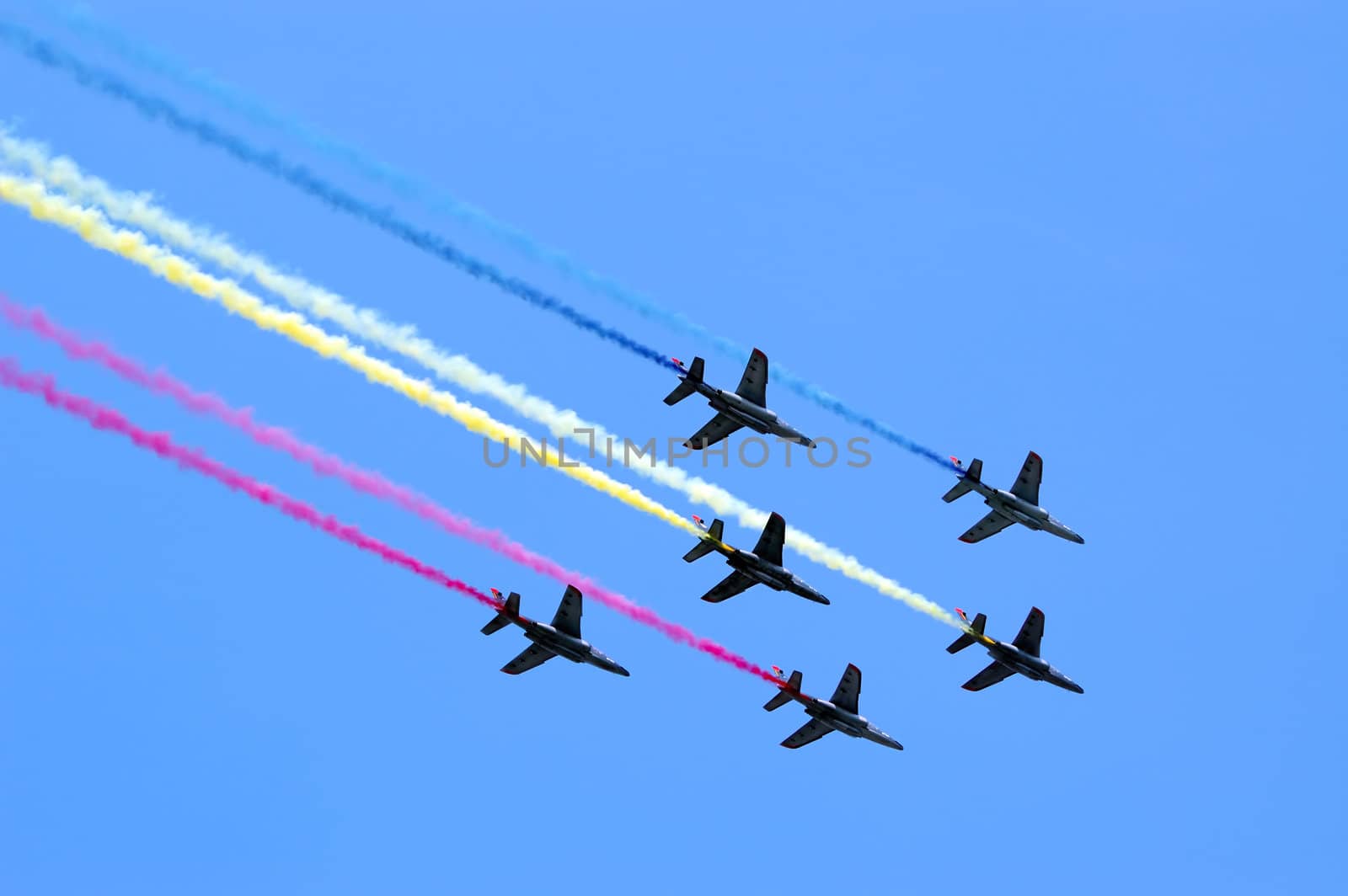 Six aircrafts in the blue sky making colour smoke