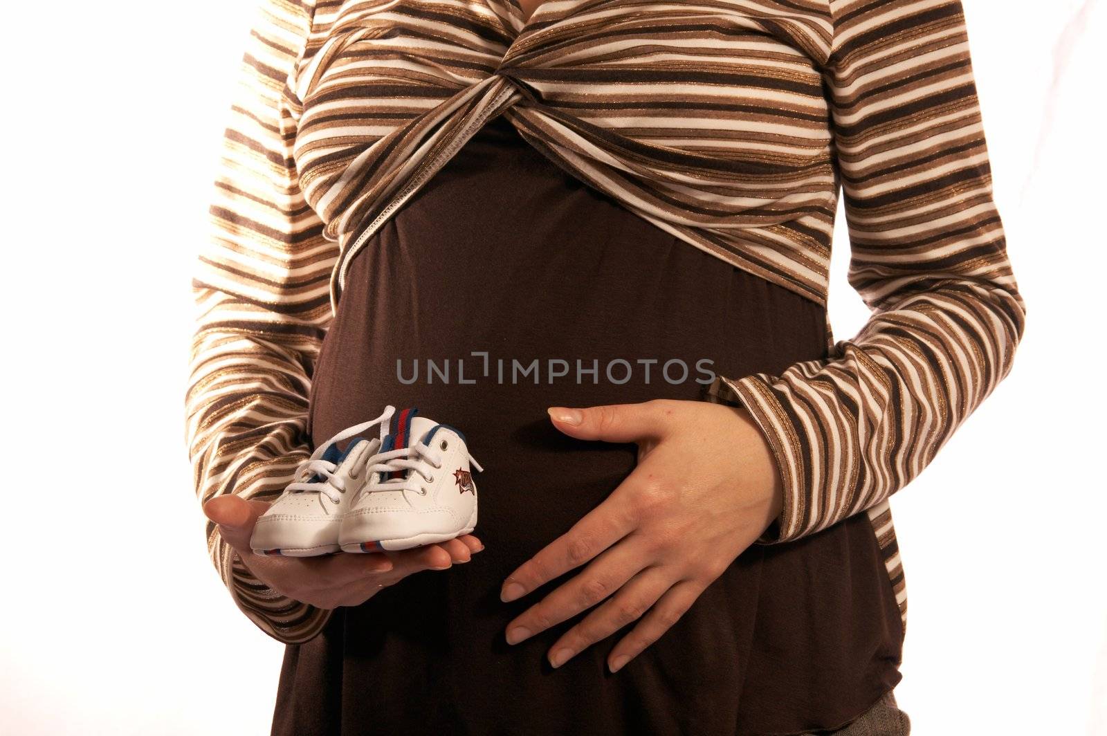 The pregnant woman on a white background. In hands holds small boots