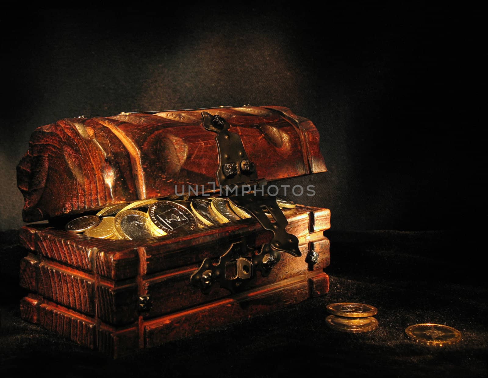 Wooden chest with coins on a dark background