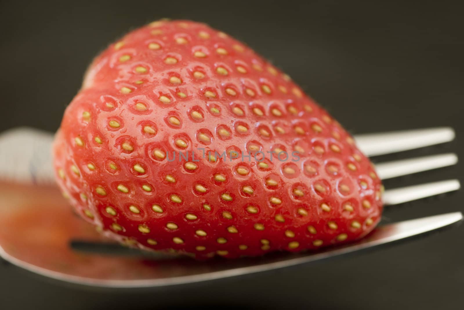a strawberry on a fork, ripe for eating