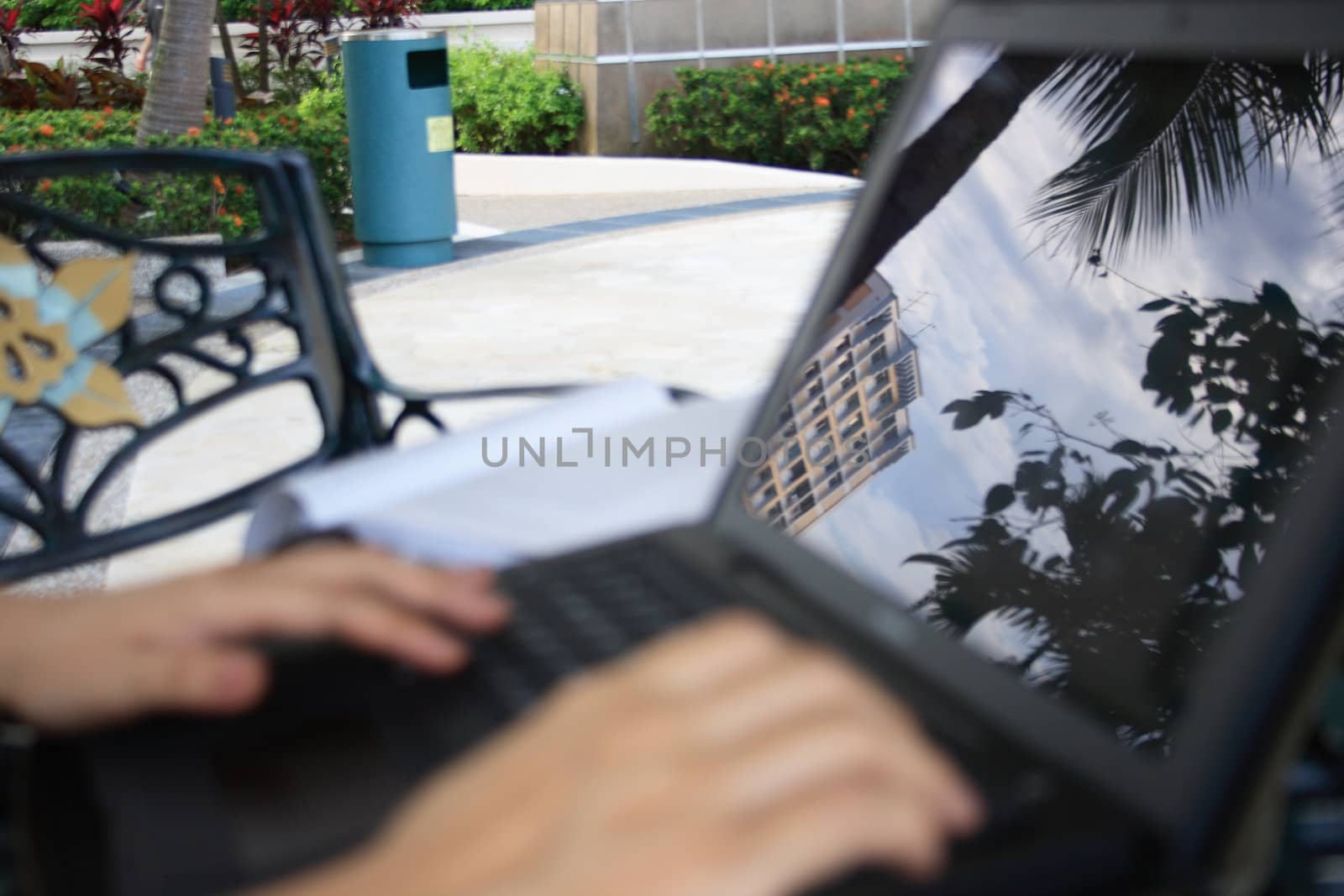 Working on on a laptop in a garden. Focus on the reflection. 
